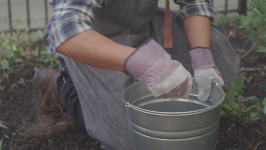 The man is putting soil in the bucket