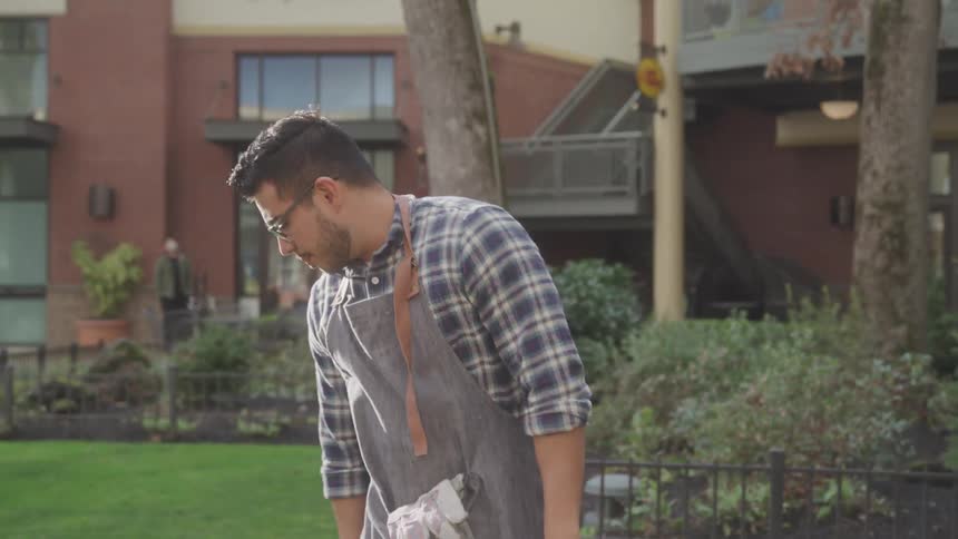 A young man is in an outdoor environment is walking while looking down searching for something