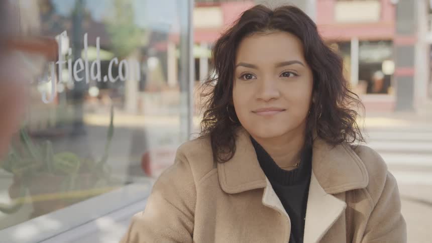 A woman is smiling outside the coffee shop