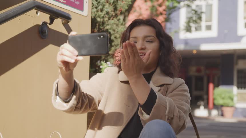 A woman blows a kiss and waves on a video call