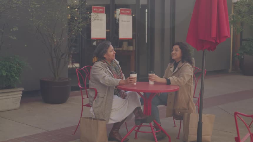A mother and daughter share a bonding moment while drinking coffee at an outdoor caf