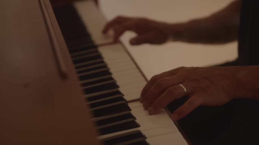A closeup of hands playing a piano focusing on the expressive movement of the fingers