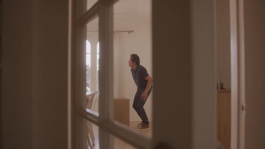 Man straightens from placing a cardboard box down in the dining room during the daytime