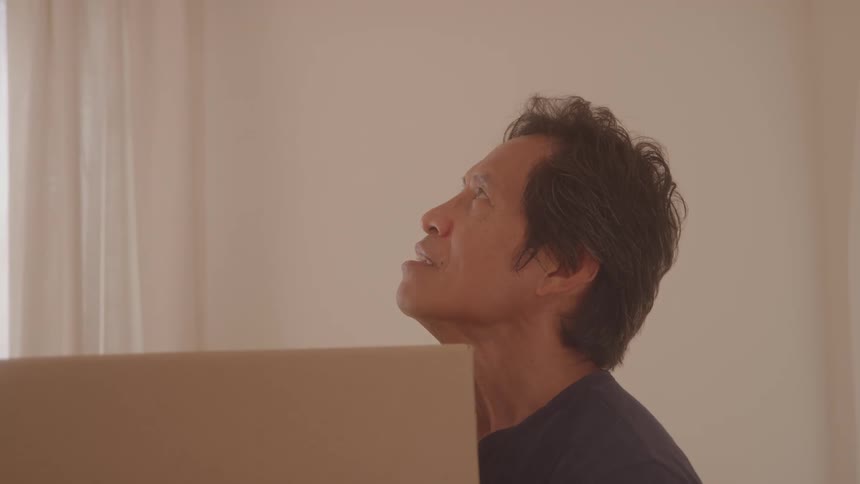 A middleaged man indoors suddenly looks up at the ceiling and smiles