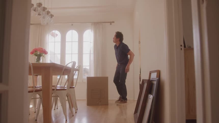 A man puts down a cardboard box in the dining room