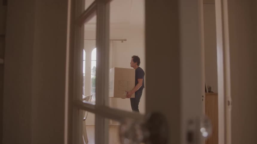 A man stands in a room holding a big box