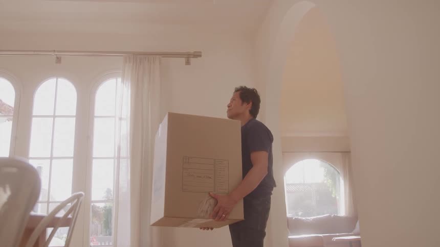 The man is carrying a box in the house