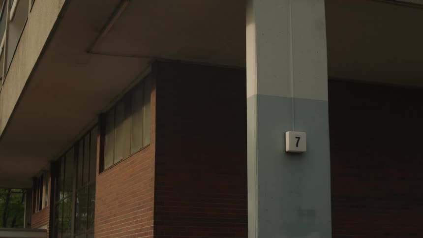 A lowangle shot captures the architectural details of a modern building focusing on a pillar with the number seven and a brick facade