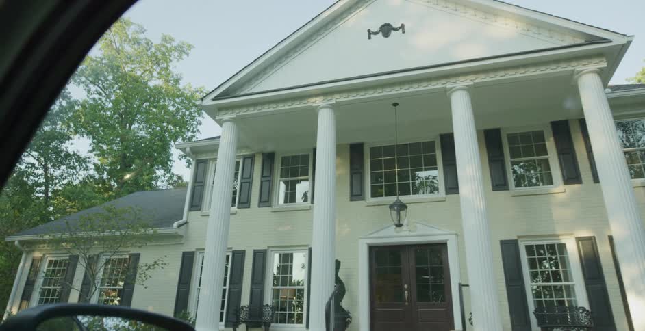 A suburban building painted white is surrounded by trees