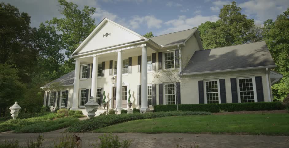 Elegant suburban house with white columns amid greenery on a sunny day