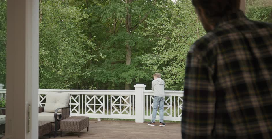 A boy looking at the forest in the yard gets called inside the home