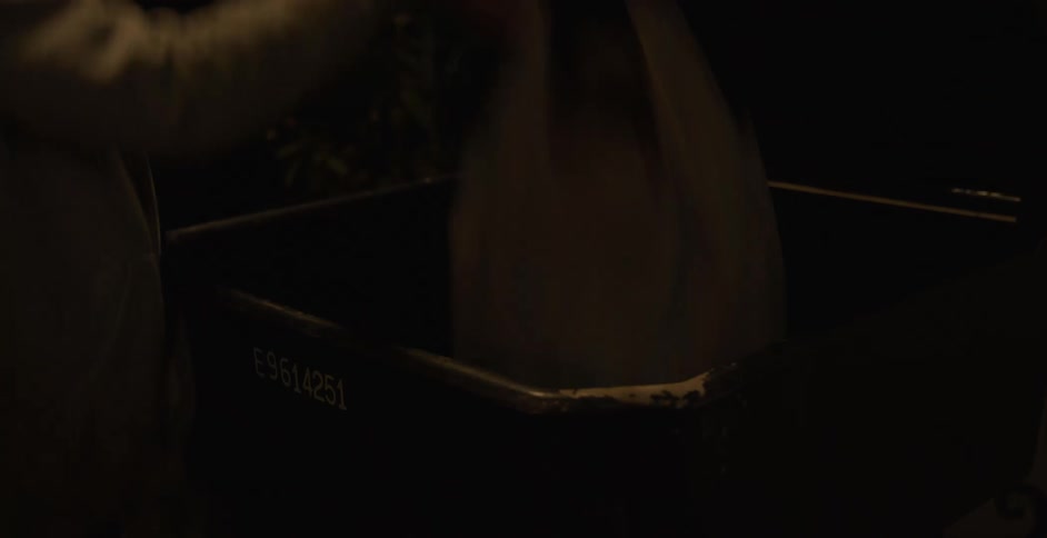 A person opens a trash bin dumps trash into it and then closes it again at night
