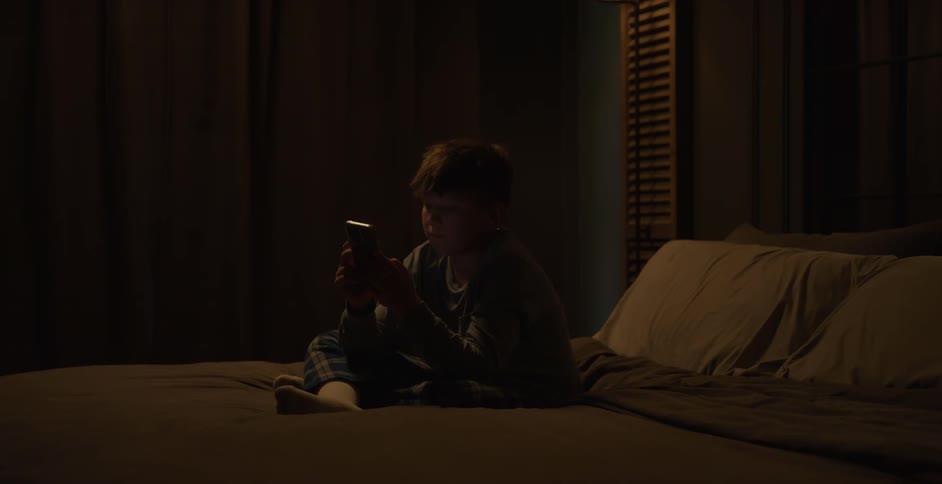 The boy types on his cell phone before bed