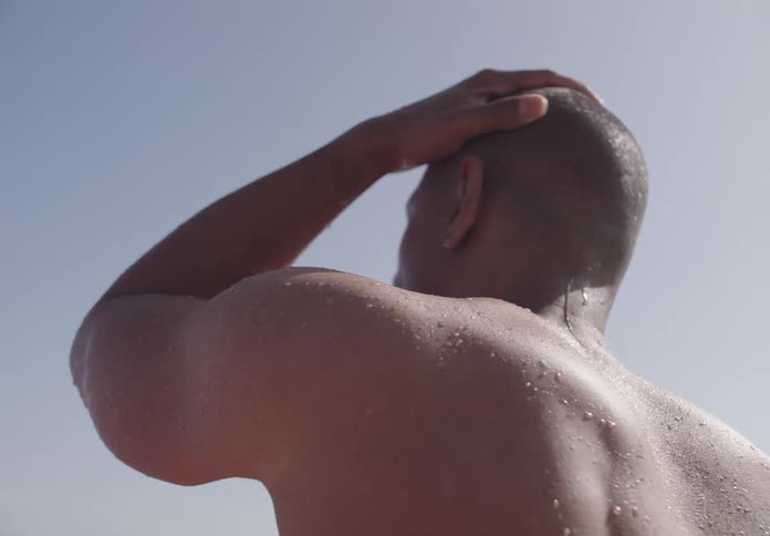 Man without a shirt and wet body touching his head