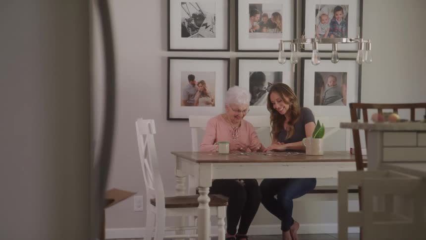 A woman is doing a puzzle with her grandmother