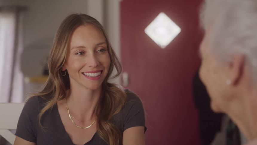 Young blonde woman smiling at an elderly person