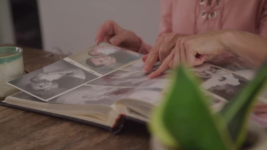 Two people look through a photo album together gently pointing at old photographs