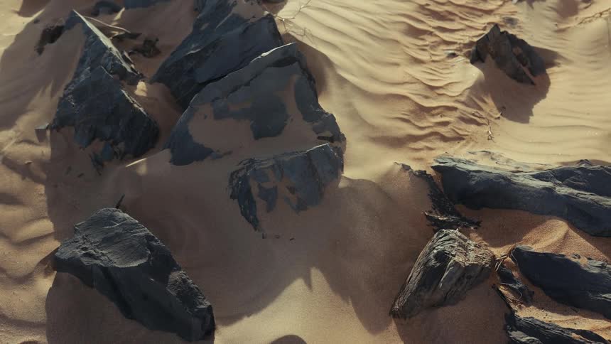 The wind blows the sand over the rocks