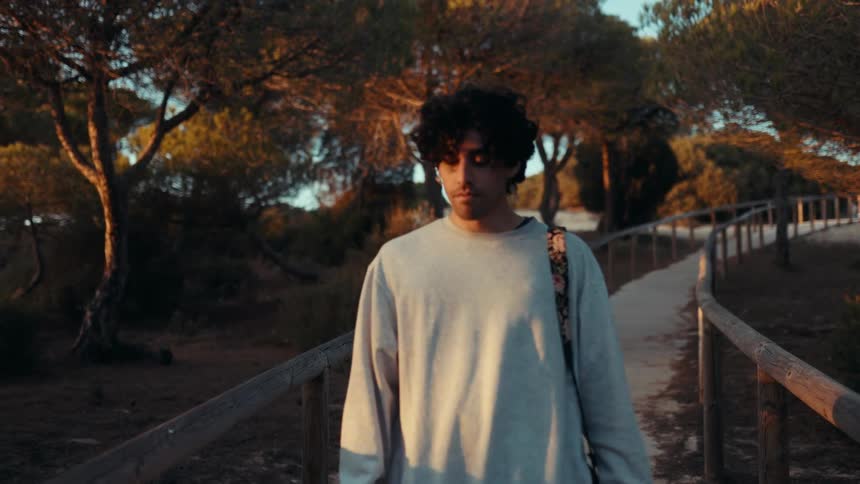 Young man walks along a forest path during golden hour