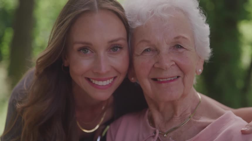 Close up portrait of a young woman and an elderly woman together outdoors during daytime