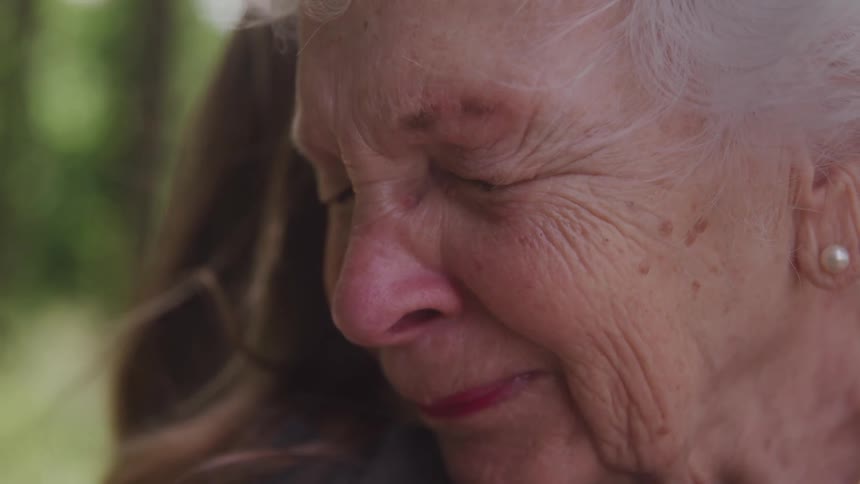 Portrait of an elderly woman hugging another woman with her eyes closed