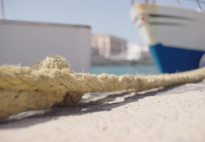 Close up of a mooring line connected to a ship at a ship dock during daytime