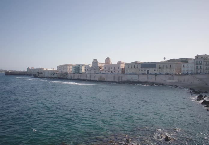 Historic coastal buildings line the waterfront under a clear sky