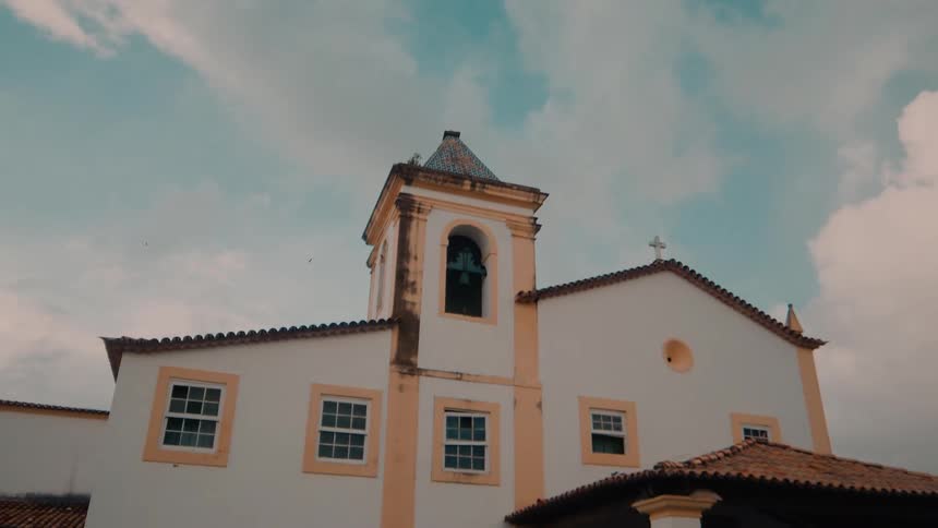 A traditional church building with a bell tower stands under a partly cloudy sky