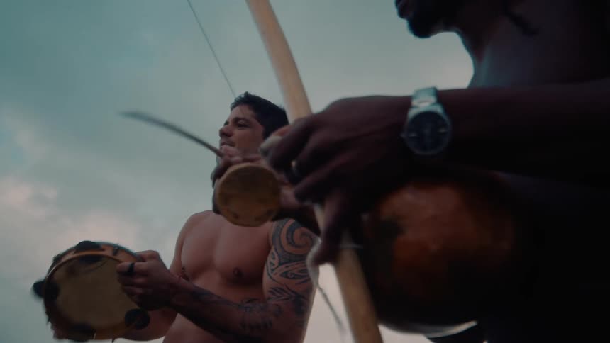 Two men are playing instruments by the ocean