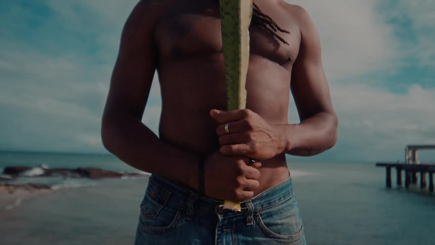 A man shirtless man is standing on the beach
