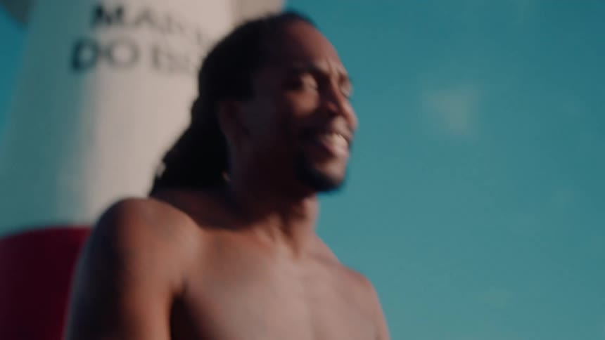 A man is tapping a drum on a sunny day