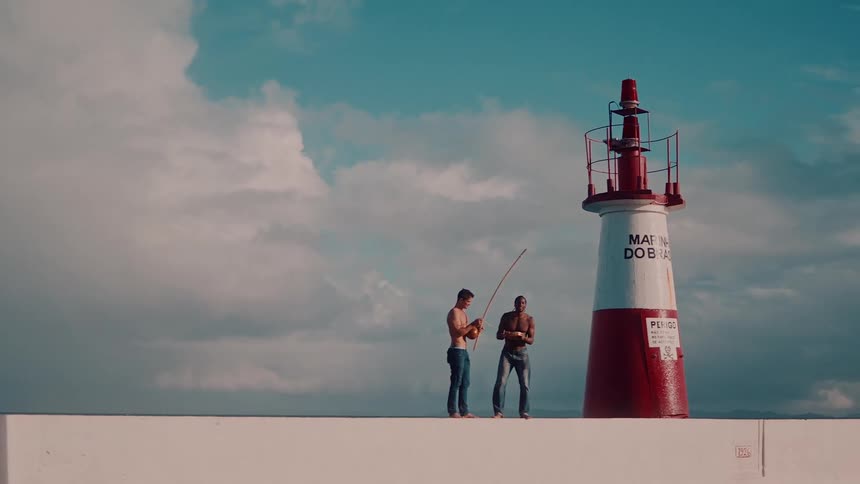 Two men are playing musical instruments on the shore