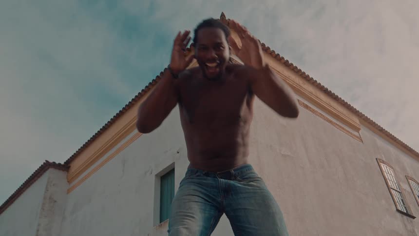 Shirtless man outdoors dancing happily
