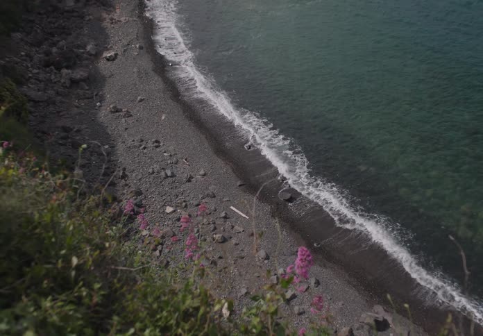 Top view of a beach with crystal clear water and rocks by the sea