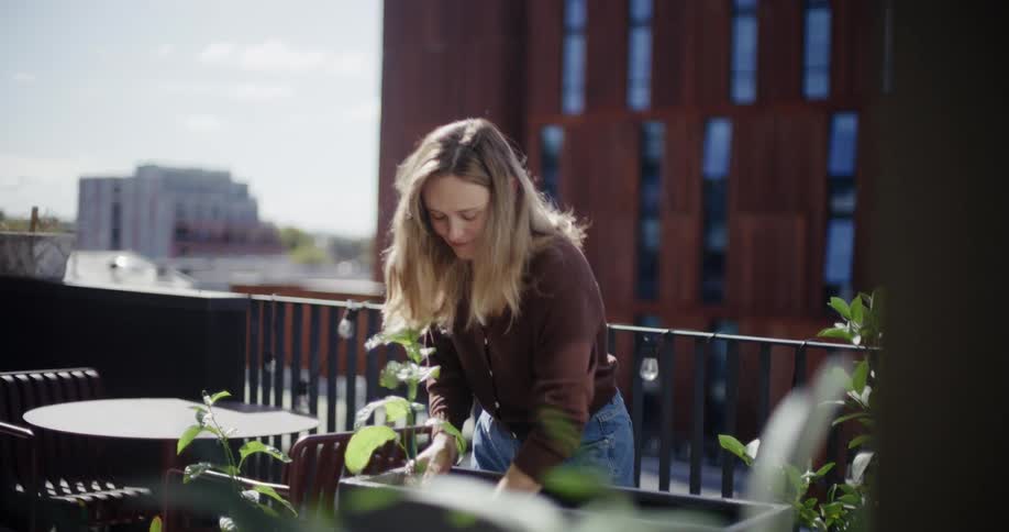 A woman tends to plants on a modern rooftop garden