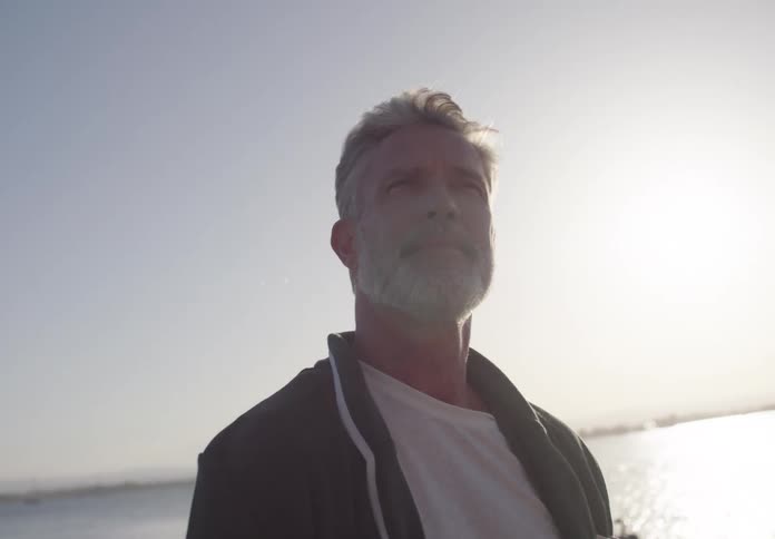The man is looking around on the beach
