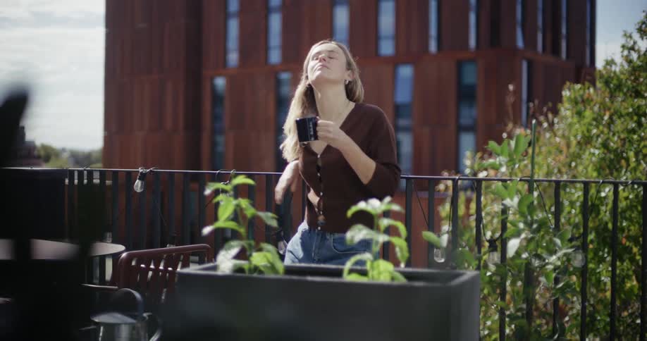 Woman relaxing drinking from a mug in an environment with green plants