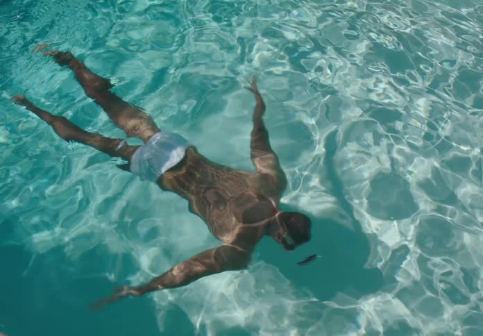 Shirtless man swimming in a pool