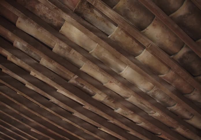 Water reflections are visible on the bamboo ceiling of a building