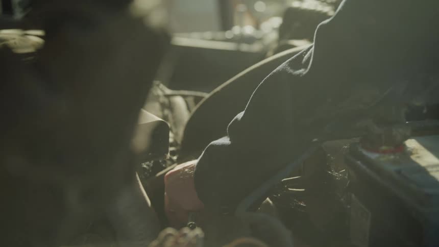 Hands of a person working on a vehicle engine