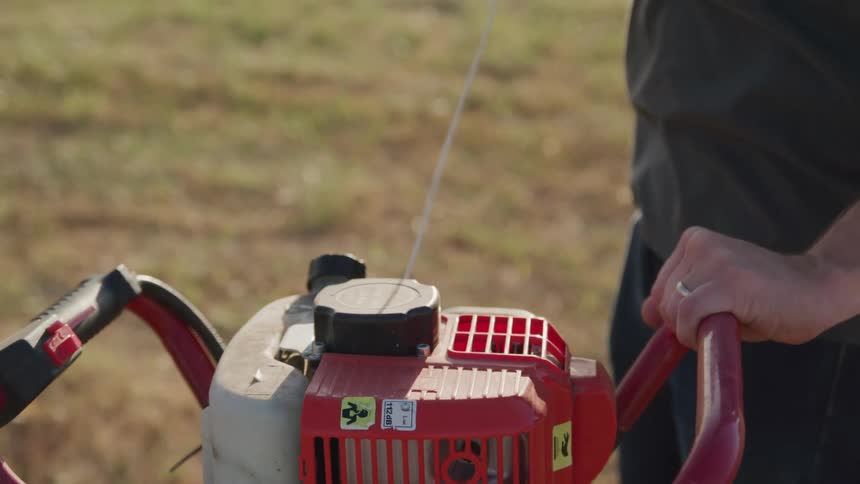 Persons arm pulling a rope on a piece of machinery