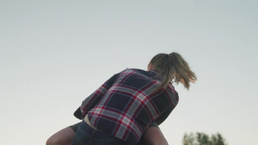 Woman leaning on the back of a man who is spinning happily