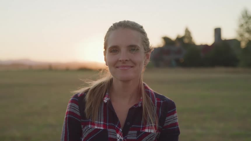 Woman in a field at dawn with a happy expression