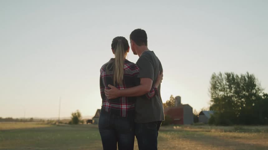 Couple hugging together in a field at dawn