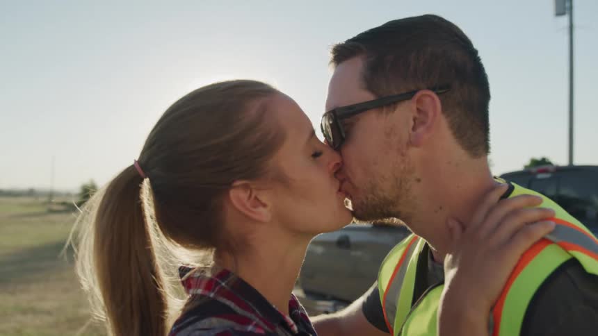 Young couple hug and kiss each other while standing outdoors before the man leaves for work in the morning
