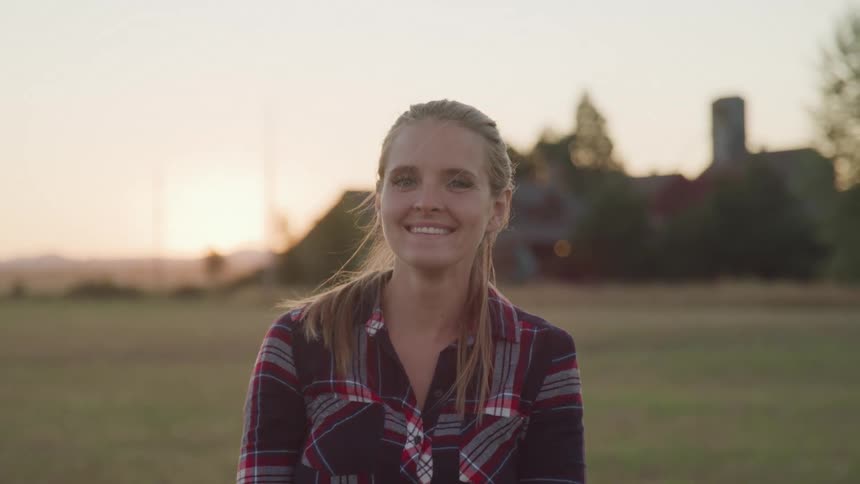 Portrait of young woman smiling while standing outdoors at sunset