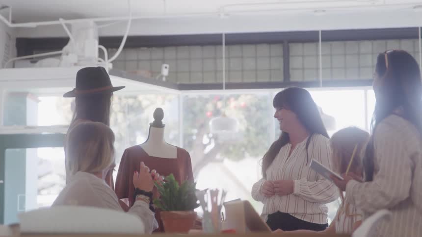 Fashion designers discuss a dress design with a client in a modern studio