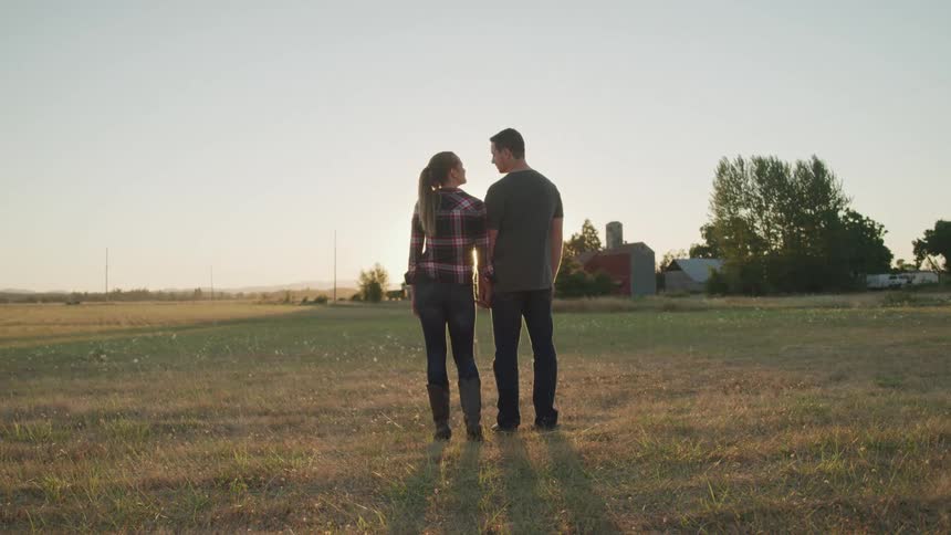 Couple holding hands in a field at sunrise