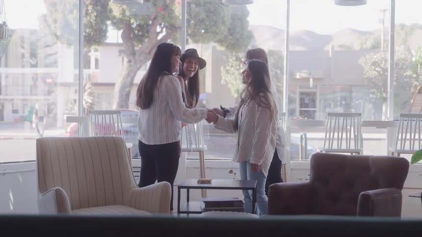 Group of four women greeting each other in an indoor space