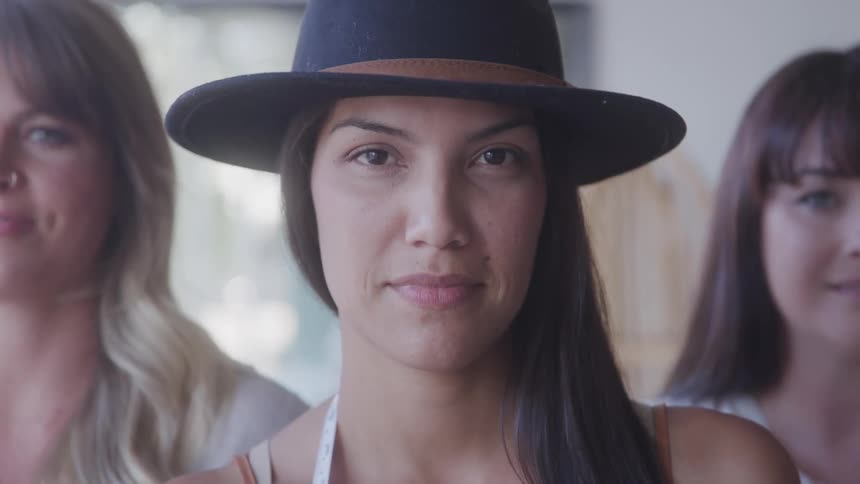 Portrait of three women with the person in the center wearing a black hat